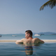 Rear view man while relaxing in swimming pool against sea - PhotoDune Item for Sale
