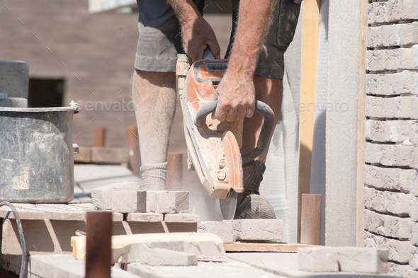 A grayhaired man saw bricks with a concrete saw of the right size for subsequent