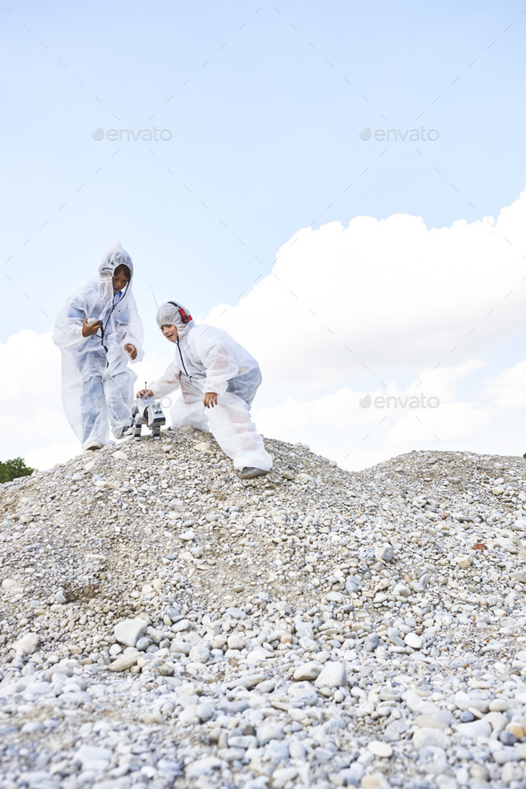 Two boys with robot on a hill dressed up as spacemen playing moon landing