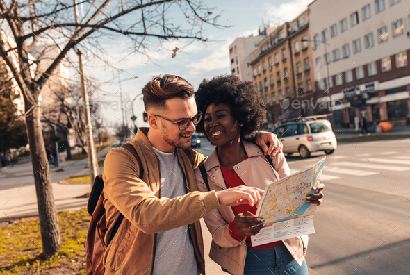 Smiling couple enjoying walking and exploring city street during the ...