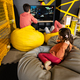 Three children playing video game console, sitting on yellow pouf in kids play center. - PhotoDune Item for Sale