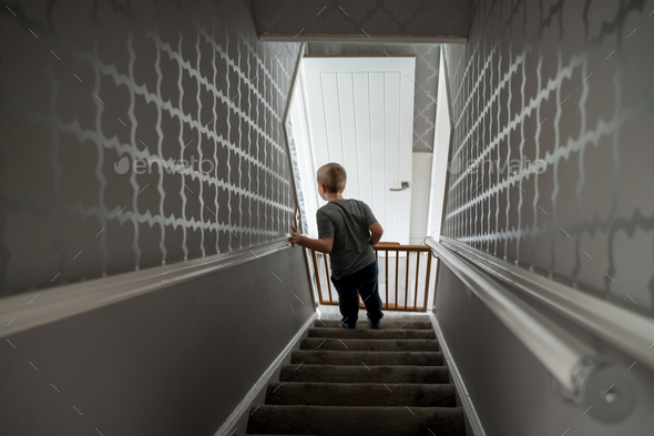Child going down the stairs at home with baby safety gate - Stock Photo - Images