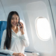 Successful young business woman working speaking on mobile phone while while sitting on aircraft - PhotoDune Item for Sale