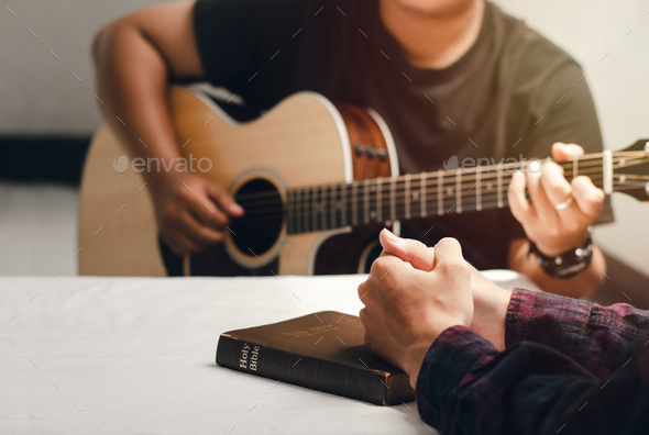 Young men play the guitar, praise God with music, and worship God together in a Christian family.