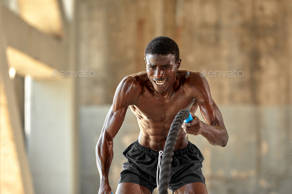 Rope workout. Sport man doing battle ropes exercise outdoor. Black male  athlete exercising, doing Stock Photo by Gerain0812