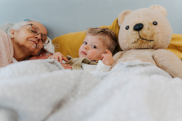 Grandmother lying with her grandson in the bed. - Stock Photo - Images
