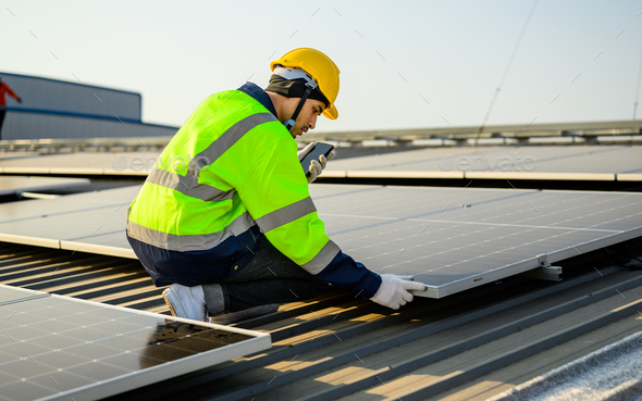 Engineer with helmet working at solar cell power plant with sunset in evening - Stock Photo - Images