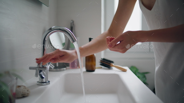 Woman washing hands faucet at home closeup. Unknown lady using bathroom sink