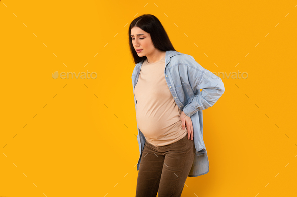 Health care concept. Pregnant lady suffering lover back pain, rubbing inflamed zone to relief ache