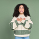 Young calm happy latin woman holding hands on chest isolated on green. - PhotoDune Item for Sale