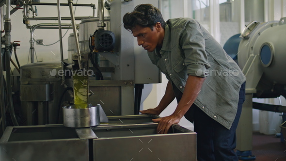 Involved worker smelling oil at fabric container closeup. Man preparing product