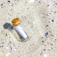 A message in a Corked Bottle on a beach. The bottle in the sand. The bottle on sandy beach. - PhotoDune Item for Sale