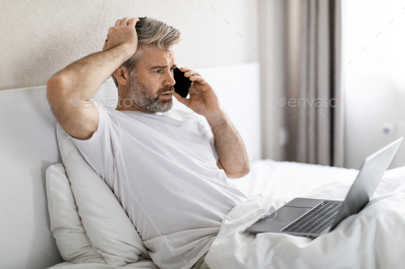Troubled middle aged man have phone call, bedroom interior