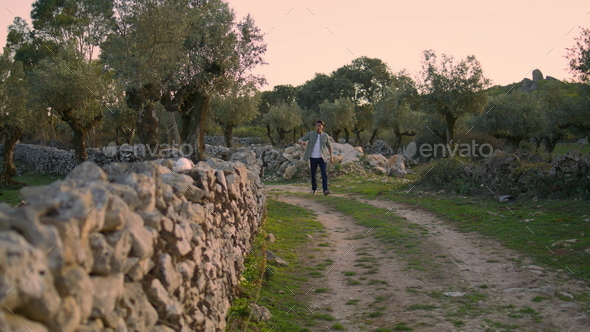 Tanned guy observing garden nature alone. Serious man crossing at rural terrain - Stock Photo - Images