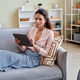 Elegant woman using digital tablet at home relaxing on sofa - PhotoDune Item for Sale