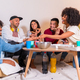 friends on a sofa eating pizza and drinking soft drinks at a home party, having fun and smiling - PhotoDune Item for Sale