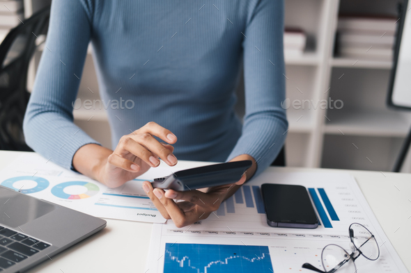 Close up view of young business woman using calculator while analyzing the information of the projec - Stock Photo - Images
