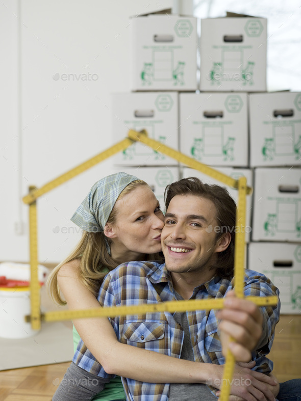 Young couple making house shape with folding rule, portrait