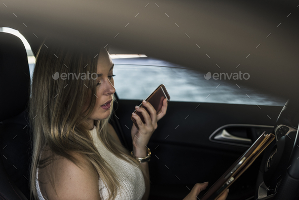 Young woman with cell phone and tablet in car