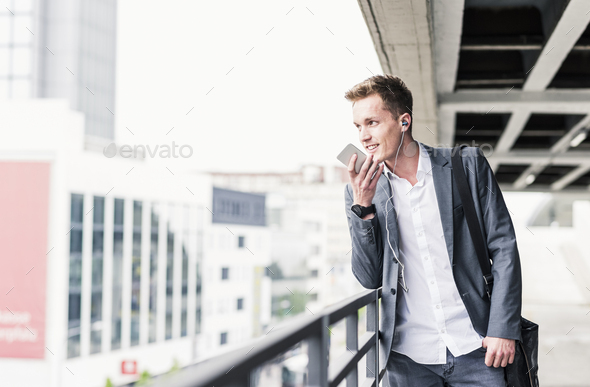 Young businessman using smartphone, standing on parking level - Stock Photo - Images