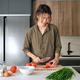 Asian young man cutting tomatoes at kitchen. - PhotoDune Item for Sale