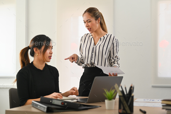 Dissatisfied team leader scolding frustrated young employee. Emotional pressure, stress at work.