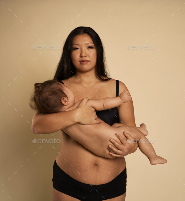 Portrait of Asian woman in underwear carrying a toddler - Stock Photo - Images