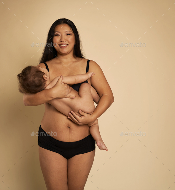 Portrait of Asian woman in underwear holding a toddler - Stock Photo - Images