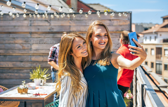 Two female friends taking a selfie in office rooftop on a summer day - Stock Photo - Images