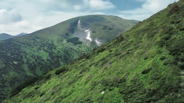 Bird-eye Wiev of a Rocky Grassy Mountain Range with a Trees and Hiking Trails on It. alt
