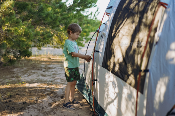 cute little caucasian boy helping to put up a tent. Family camping concept - Stock Photo - Images