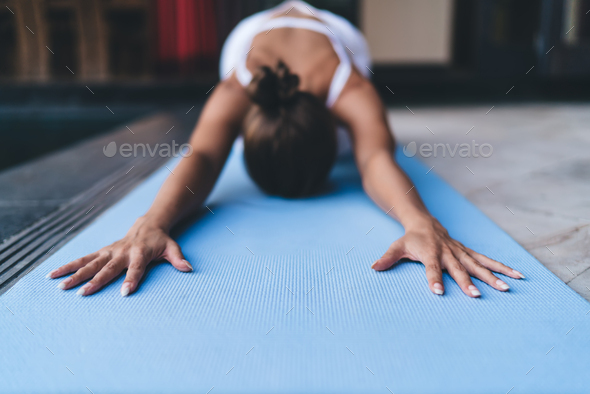 Unrecognizable fit girl in sportswear enjoying harmony meditation during pilates training