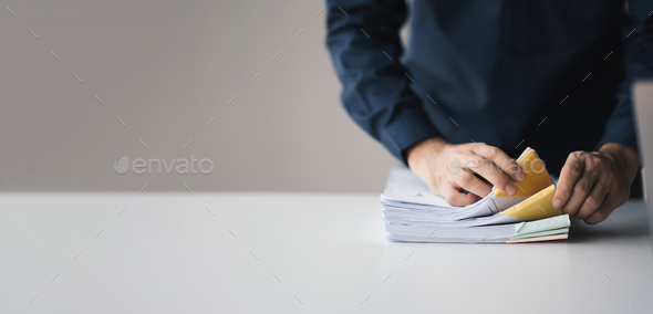 Businessman hand pick up stack overload documents, trying to organize and categorize the document in