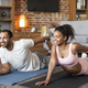 Cheerful young black family in sportswear doing leg stretching exercises on mat on floor, enjoy - PhotoDune Item for Sale