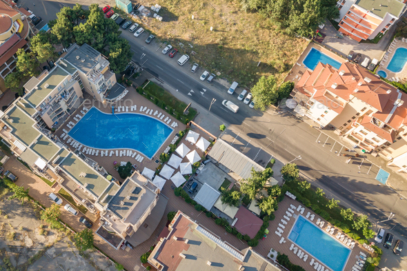 Top down aerial view of hotels roofs, streets with parked cars and swimming pools