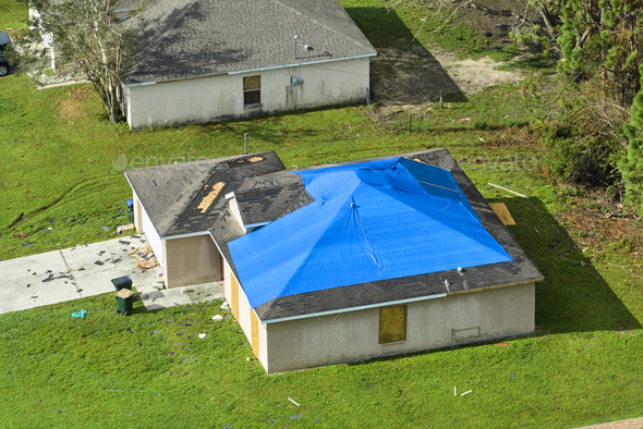 Top view of leaking house roof covered with protective tarp sheets against rain water