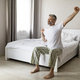 Happy handsome middle aged man sitting on bed and stretching - PhotoDune Item for Sale