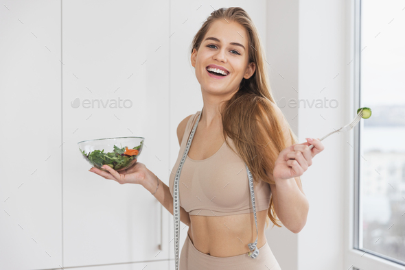 Beautiful sport girl in sportswear enjoy eat clean vegetables after exercise for health in house.