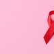 A silk red ribbon in the form of a bow on a pink background, a symbol of the fight against AIDS - PhotoDune Item for Sale