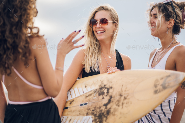 Three beautiful woman friends posing with surfboard on a beach - Stock Photo - Images