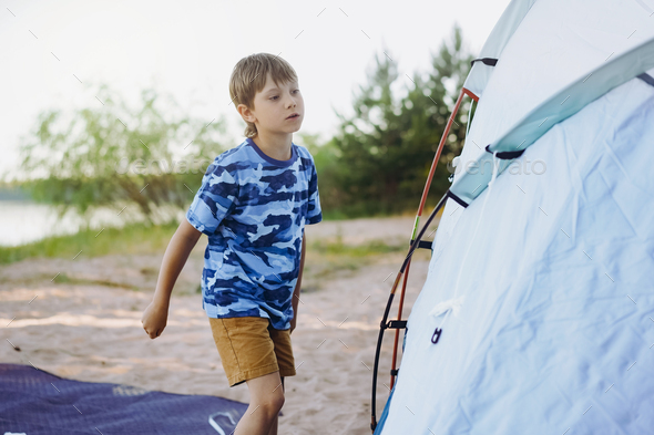 cute little caucasian boy helping to put up a tent. Family camping concept - Stock Photo - Images
