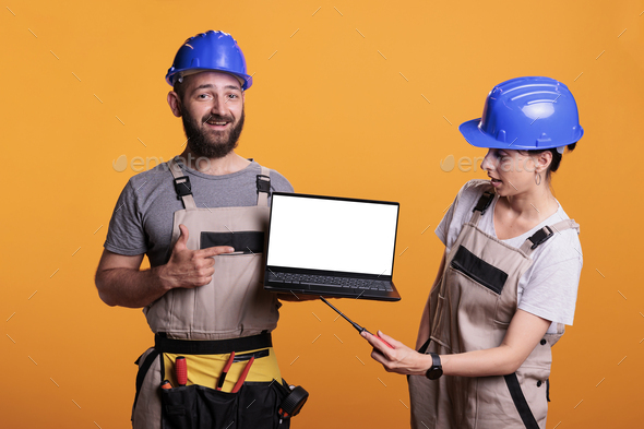 Cheerful renovators pointing at white laptop screen - Stock Photo - Images