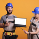 Cheerful renovators pointing at white laptop screen - PhotoDune Item for Sale