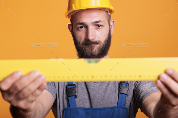 Confident male carpenter looking at construction leveler - Stock Photo - Images