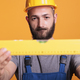 Confident male carpenter looking at construction leveler - PhotoDune Item for Sale