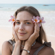Face of beautiful young adult blond woman holding flowers close to face at beach - PhotoDune Item for Sale