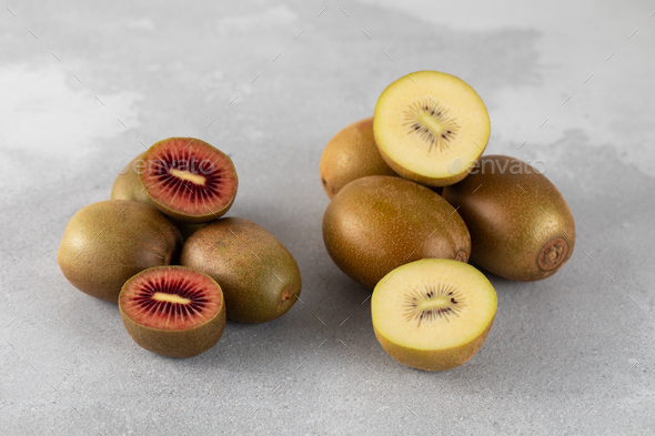 Red and gold kiwi whole and halves on a gray table. Different varieties of kiwi.