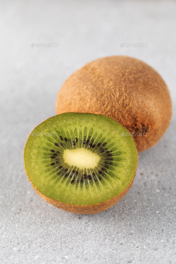 Green ripe kiwi half and whole on grey table. Place for text. Horizontal photo. - Stock Photo - Images