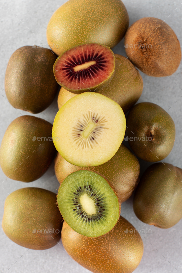 Different varieties of kiwi lie in a pile on the table. Halves of red, yellow and green kiwi. - Stock Photo - Images