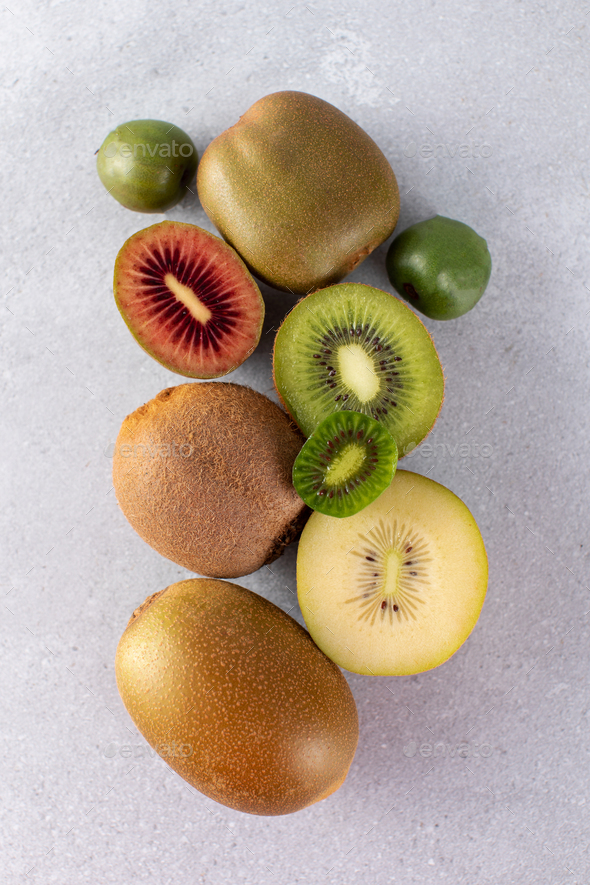 Different varieties of kiwi lie in a pile on the table. Halves of red, yellow, green kiwi - Stock Photo - Images